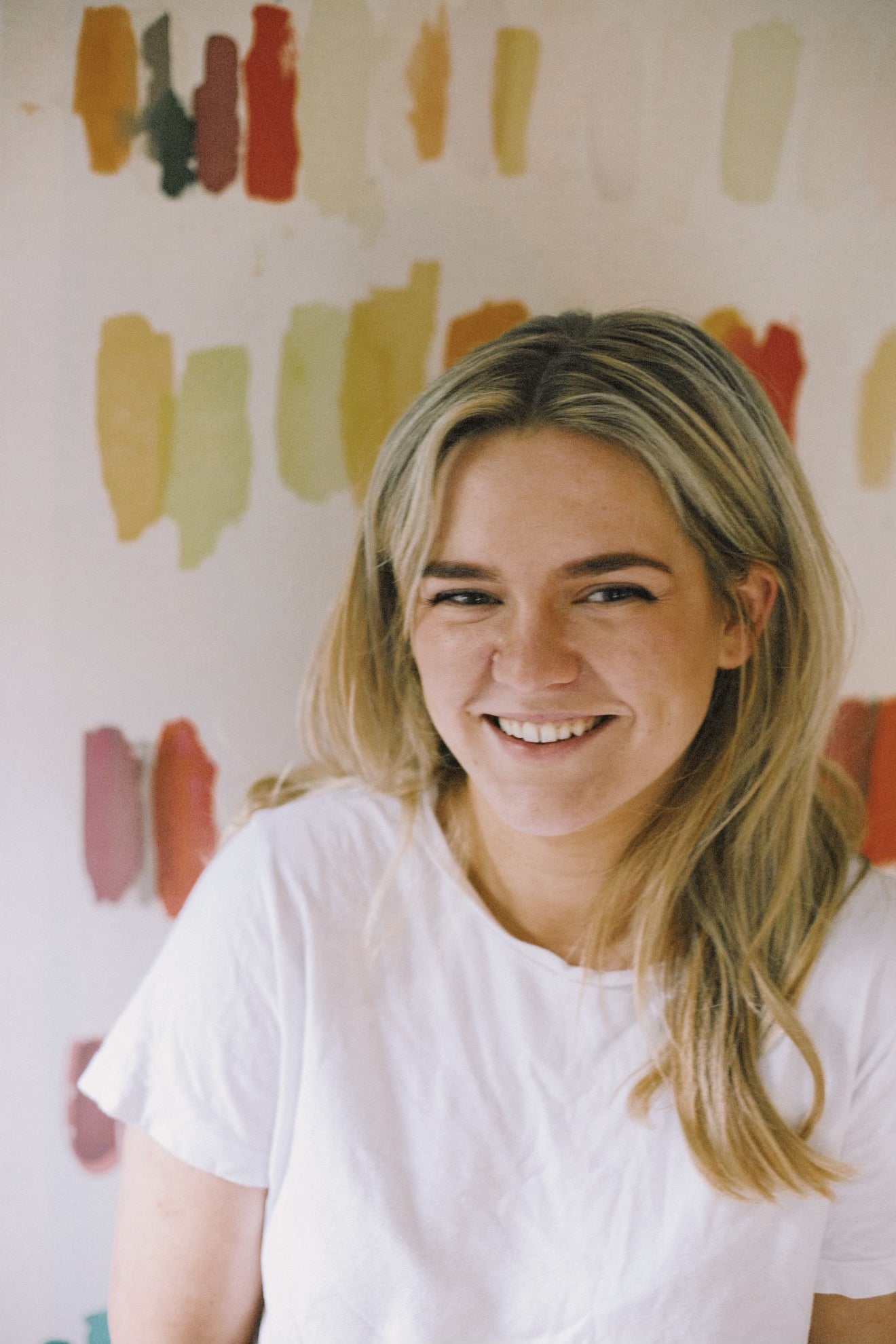 woman smiling in front of colorful abstract painting