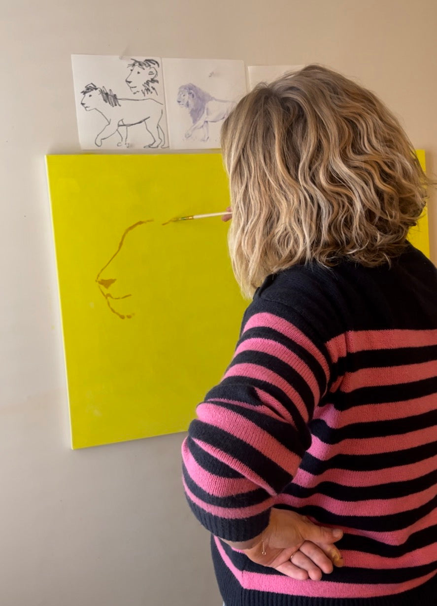 Person wearing a striped sweater looking at drawings on a wall